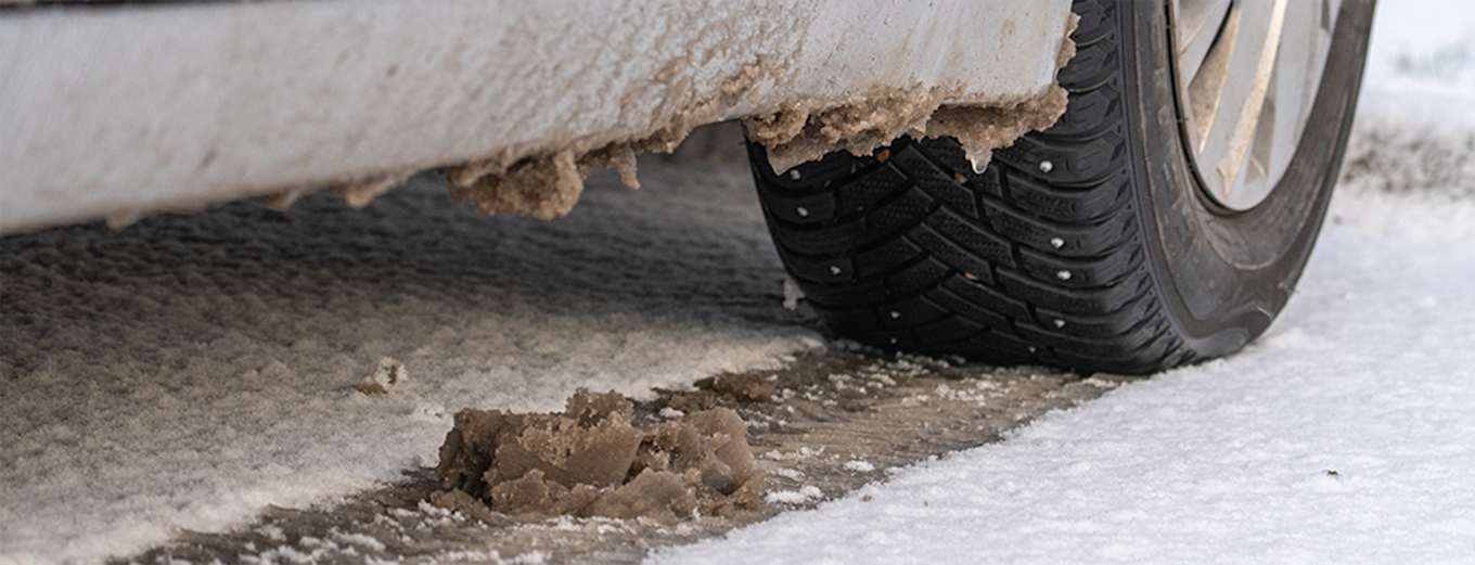 Bild på ett vinterdäck på en bil som kör på snöig väg med slask och vägsalt.