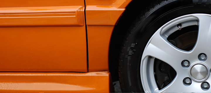 Närbild på bildäck på orange bil.
