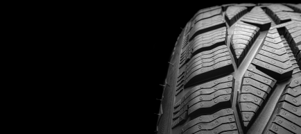 Närbild på bildäck med tydligt mönster mot svart bakgrund.